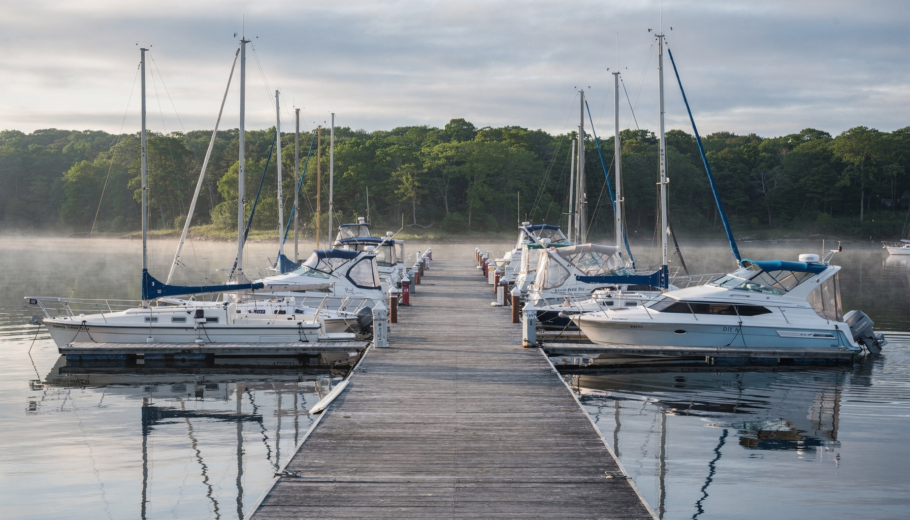A row of boats along a Connecticut marina dock on a calm morning, the kind of fleet an independent surveyor works across